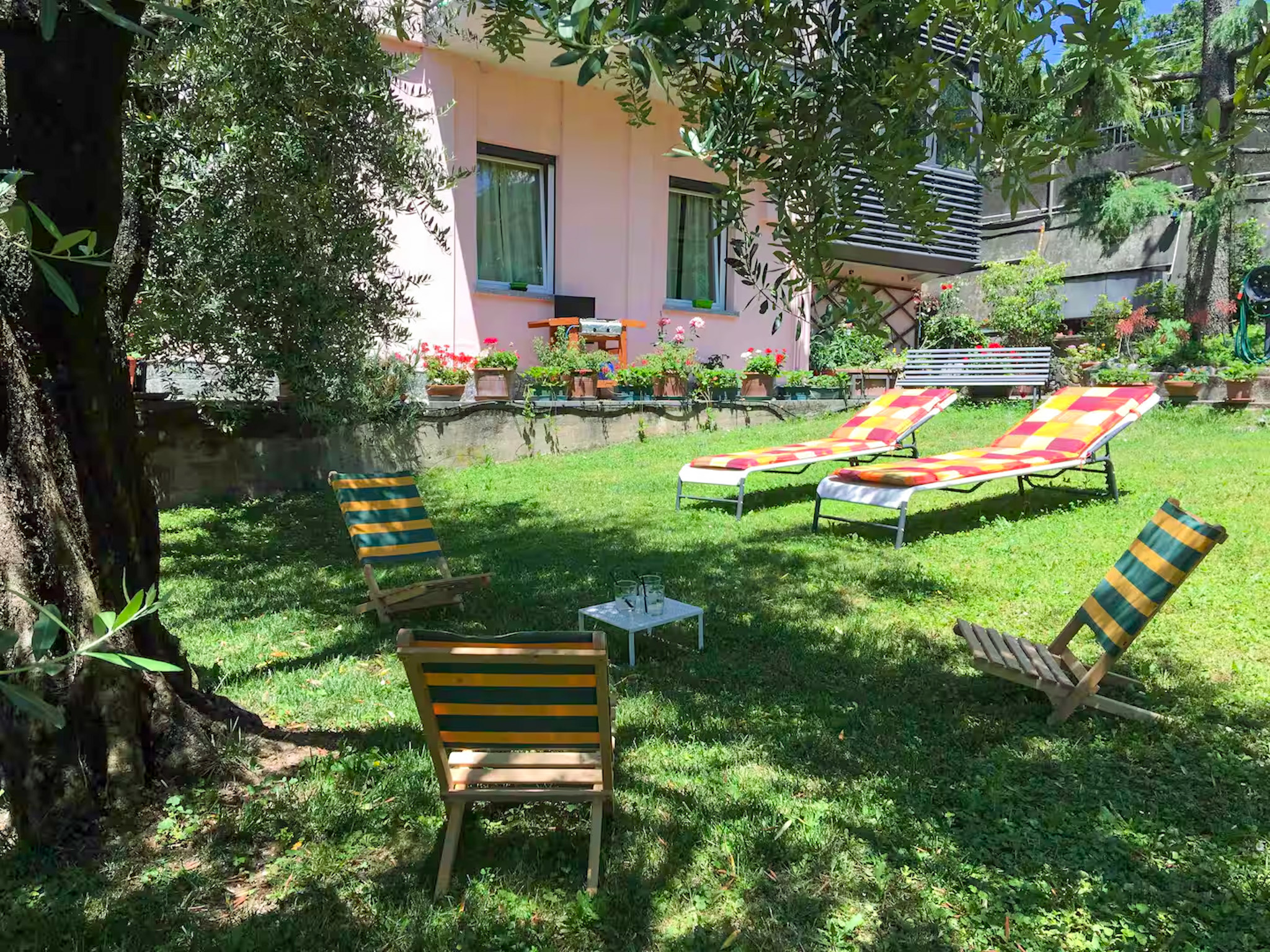Area relax nel giardino de La Casa degli Ulivi con lettini e vista panoramica sul lago